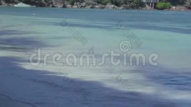 塞舌尔。 普拉斯林岛。 清澈的<strong>海水</strong>在海滩上<strong>翻滚</strong>着波浪，白色的泡沫接近。 小房子藏在里面